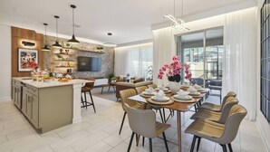 A modern kitchen with a central island, dining area with chairs, and a large window with curtains. - Family 4BR Home w/ Pool at Storey Lake (Kissimmee)