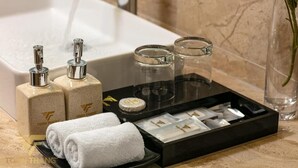 A bathroom counter with a white towel, two soap dispensers, a glass container, and a tray of toiletries. - Toan Thang Hotel by Bay Luxury (Hanoi)