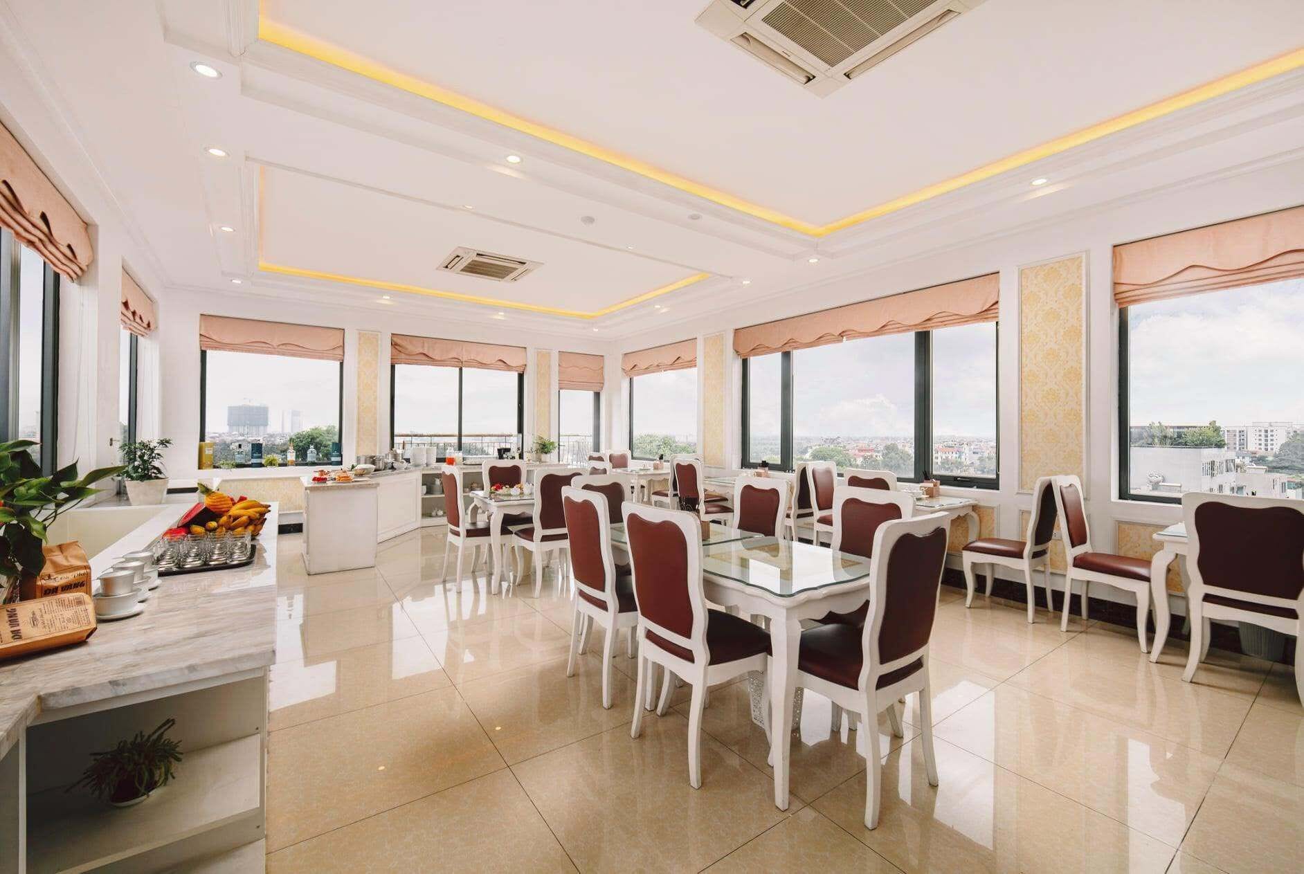 A modern dining area with multiple tables and chairs, large windows with city views, and a clean, well-lit interior.