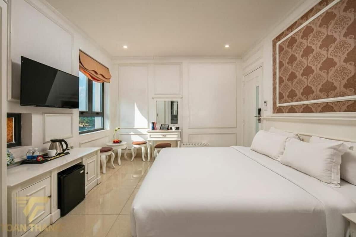 Ein Hotelzimmer mit einem großen Bett, einem Fernseher, einem Schreibtisch mit Stuhl und einem kleinen Tisch mit Stuhl.