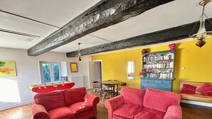 A room with two red sofas, a wooden dining table, and a bookshelf. - Cosy rural 5 bedroom home with games room, pet friendly, garden, bbq! (Ger)