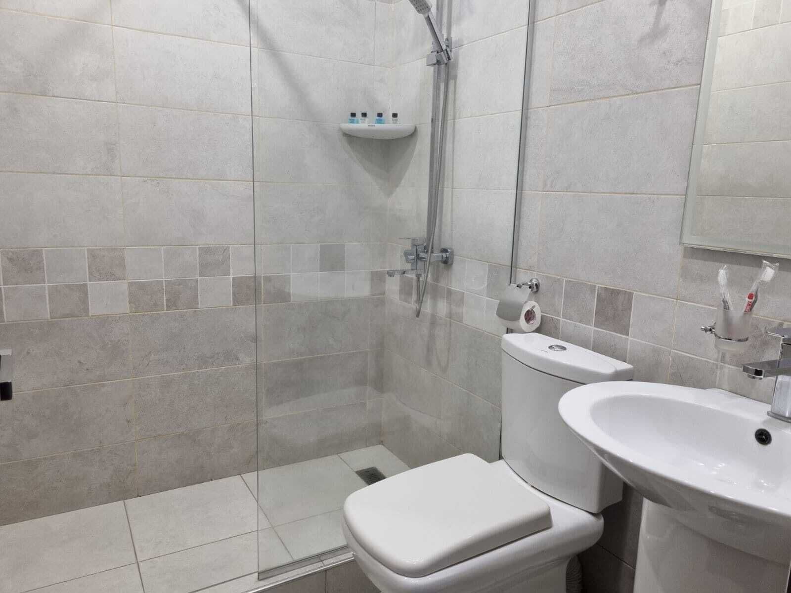 A modern bathroom with a toilet, sink, and shower.