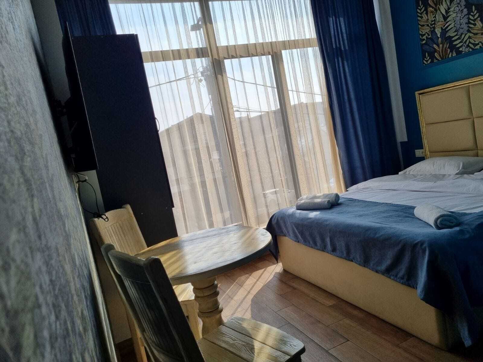 A hotel room with a bed, a desk, a chair, and a window with curtains.