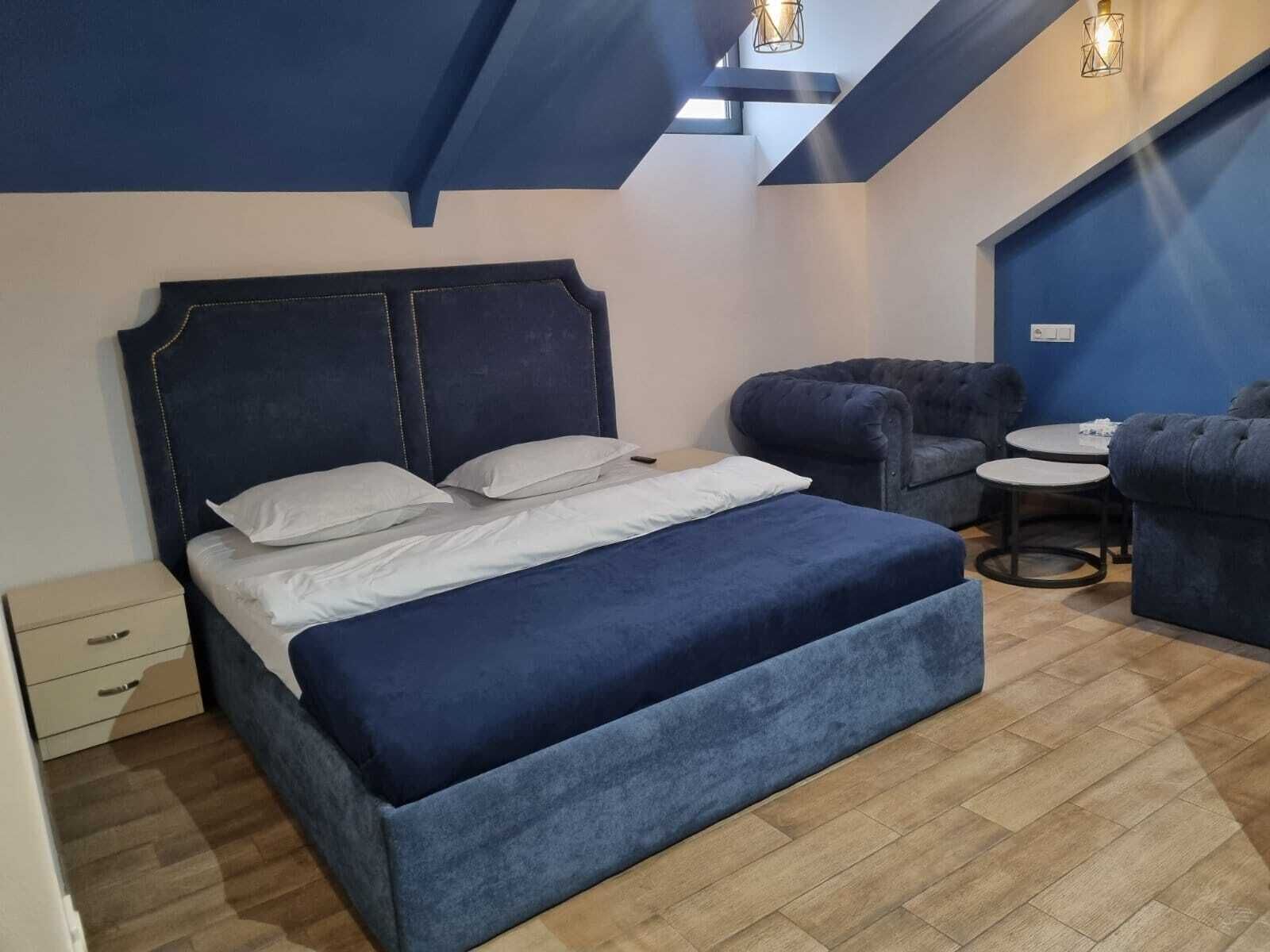 Ein Schlafzimmer mit einem großen Bett, einem Sessel, einem kleinen Tisch und einer Kommode.