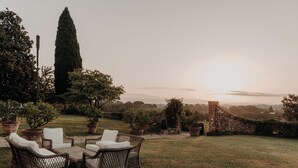 An outdoor seating area with wicker furniture and potted plants, overlooking a scenic landscape. - Buonvisi B&B (Lucca)
