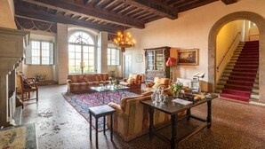 A spacious living room with a high wooden ceiling, a fireplace, and a staircase leading to an upper floor. - Buonvisi B&B (Lucca)
