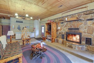 Interior acogedor de una cabaña con chimenea de piedra, decoración rústica y un letrero de bienvenida.