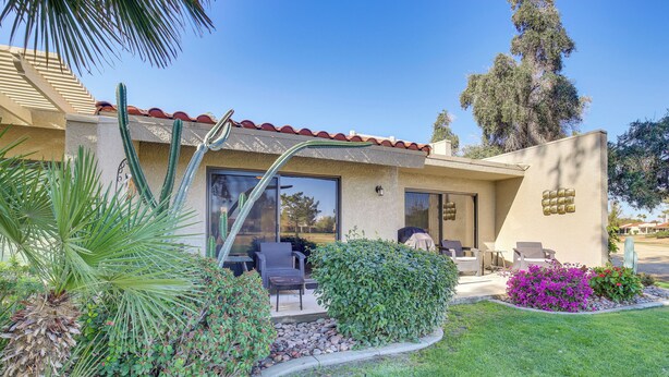 A building with a patio area, outdoor seating, and a well-maintained garden with various plants and a small water feature. - Palm Desert Condo w/ Patio & Golf Course Views! (Palm Desert)