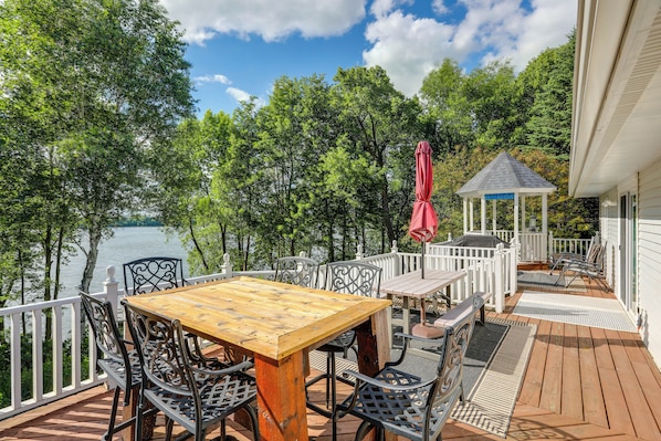 A wooden deck with outdoor furniture, a gazebo, and a view of a lake.