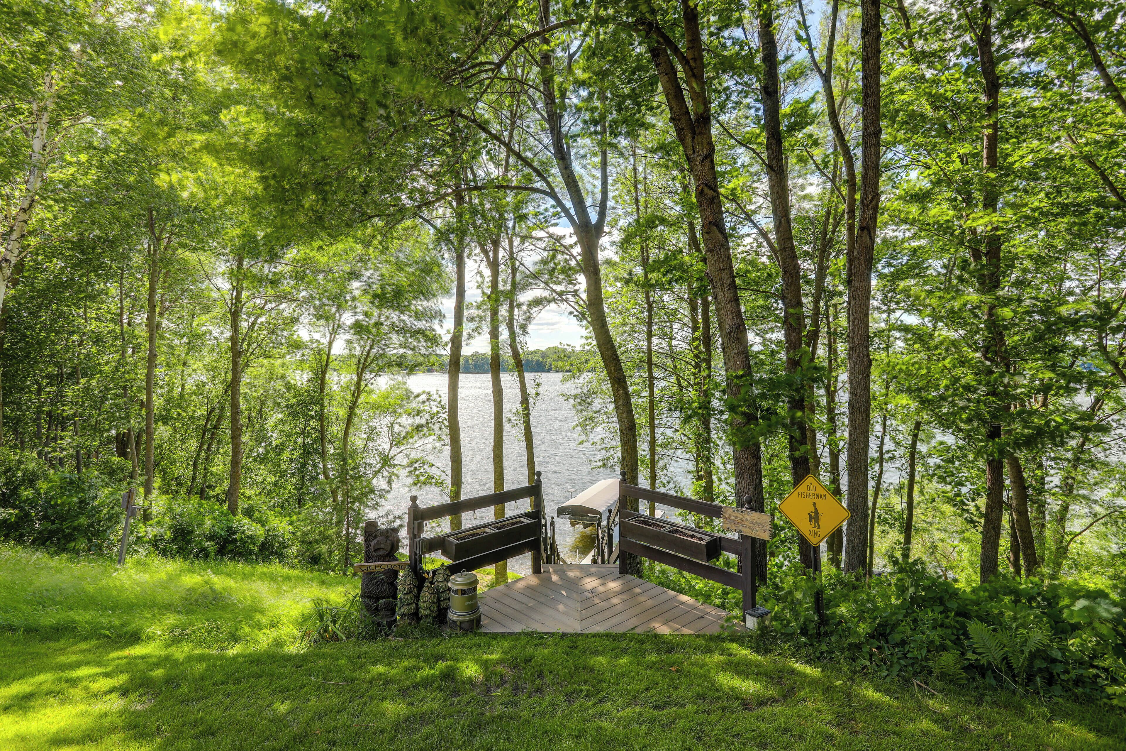 A wooden deck leading to a lake surrounded by trees.