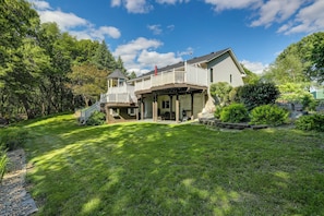 A two-story house with a covered porch, a small deck, and a well-maintained lawn.