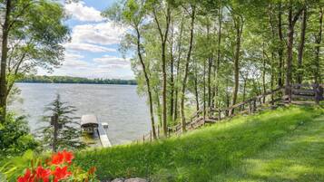 A lakeside view with a dock, wooden stairs, and lush greenery.