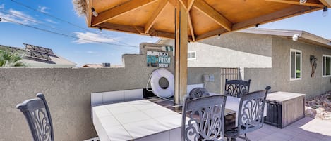 An outdoor patio with a wooden table and chairs, a thatched umbrella, and a sign reading "LAX FRESH NEW".