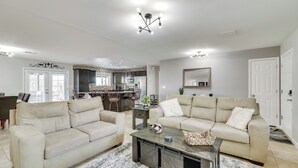 A spacious living room with two beige sofas, a coffee table, and a chandelier.