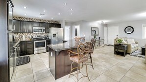 A modern kitchen with dark cabinets, stainless steel appliances, and a central island with bar stools.