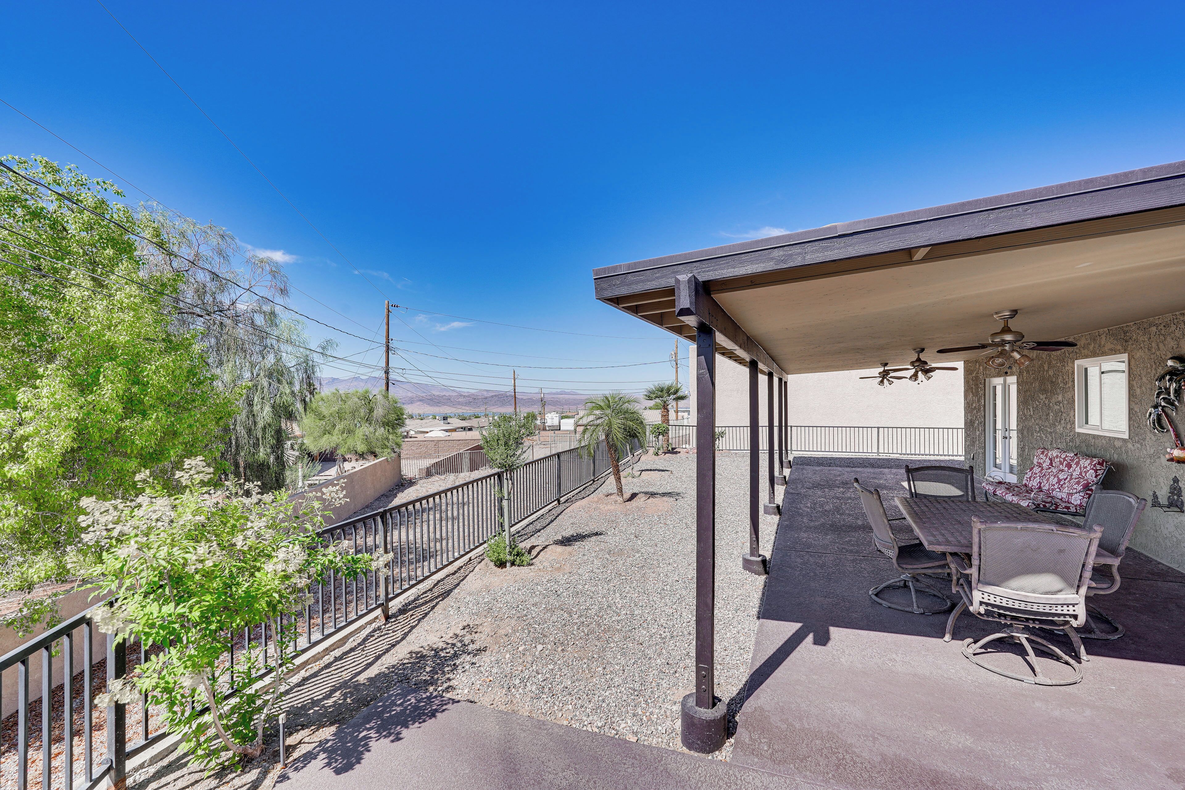 A covered patio with outdoor furniture, a view of the surrounding landscape, and a clear blue sky.