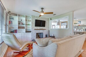 A living room with a fireplace, bookshelves, and a television. - Pensacola Home in Historic East Hill Neighborhood (Pensacola)