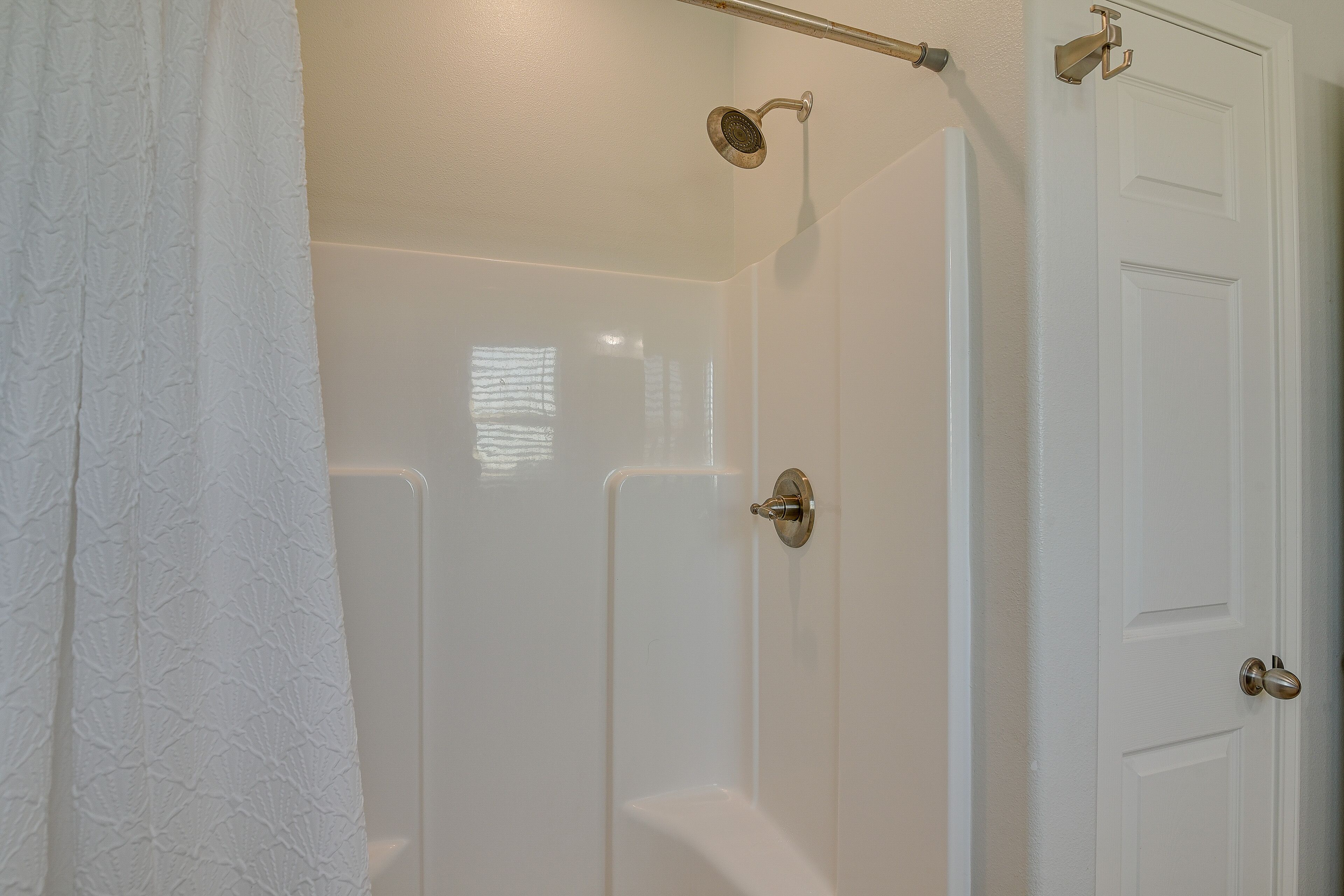 A bathroom with a shower, a toilet, and a door.