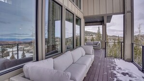 A modern outdoor deck with a sofa and chairs, large windows offering a view of a snowy landscape. - Spacious Utah Escape w/ Balcony & Mountain Views! (Brian Head)