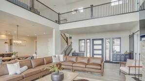 A spacious living area with a high ceiling, a leather sofa set, a wooden coffee table, and a staircase leading to an upper level. - Spacious Utah Escape w/ Balcony & Mountain Views! (Brian Head)
