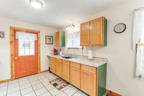 A kitchen with wooden cabinets, a sink, and a clock on the wall.
