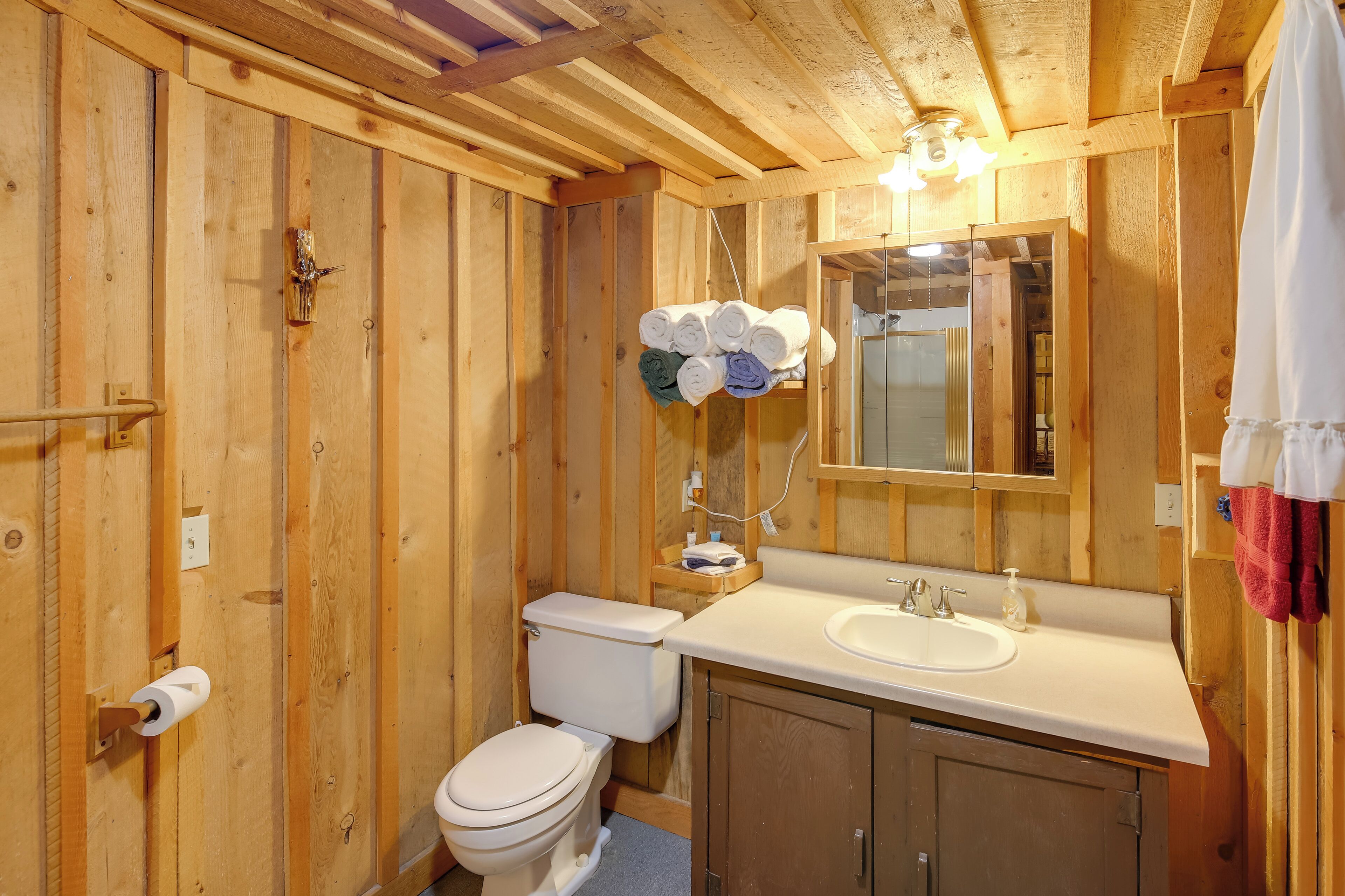 Une salle de bain en bois avec des toilettes, un lavabo et un miroir.