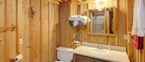 Une salle de bain en bois avec des toilettes, un lavabo et un miroir.
