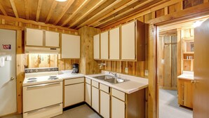 Una cucina con pareti in legno, un fornello, un lavello e pensili.