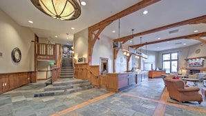A spacious lobby with a stone floor, wooden staircase, and a reception desk. - Ski-in/ski-out Park City Studio w/ Pool Access! (Park City)