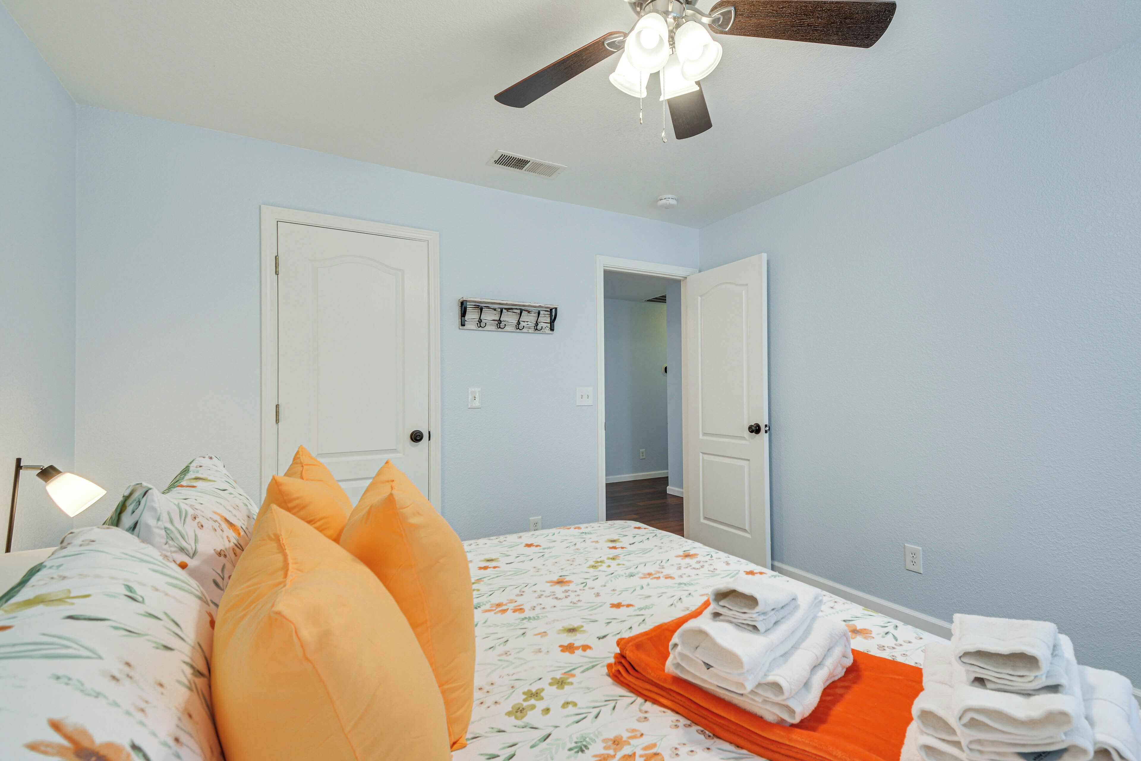 A bedroom with a bed, pillows, a ceiling fan, and a door.