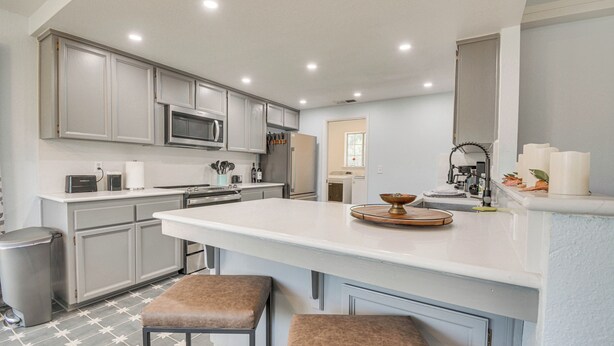 A modern kitchen with grey cabinets, a central island, and a stainless steel refrigerator. - Bright + Cozy Mariposa Getaway: 46 Mi to Yosemite! (Mariposa)