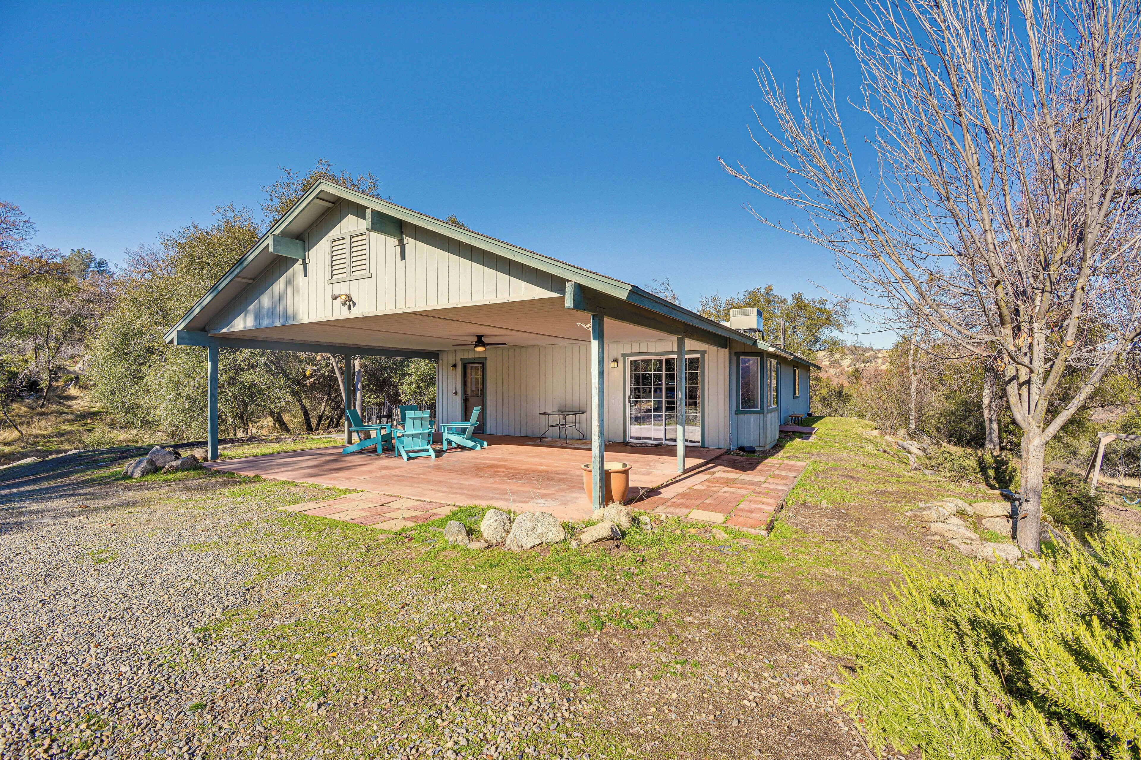 A single-story house with a covered patio, a small table, and two chairs.