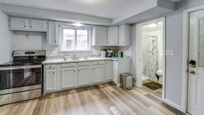 A modern kitchen with white cabinets, a stainless steel oven, and a window above the sink.