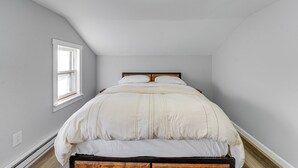 A bedroom with a single bed, a window, and a sloped ceiling.