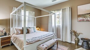A four-poster bed with a bench, bedside tables, and a large window with curtains. - Cozy Alpine Cottage Near Casinos & Trails! (Alpine)