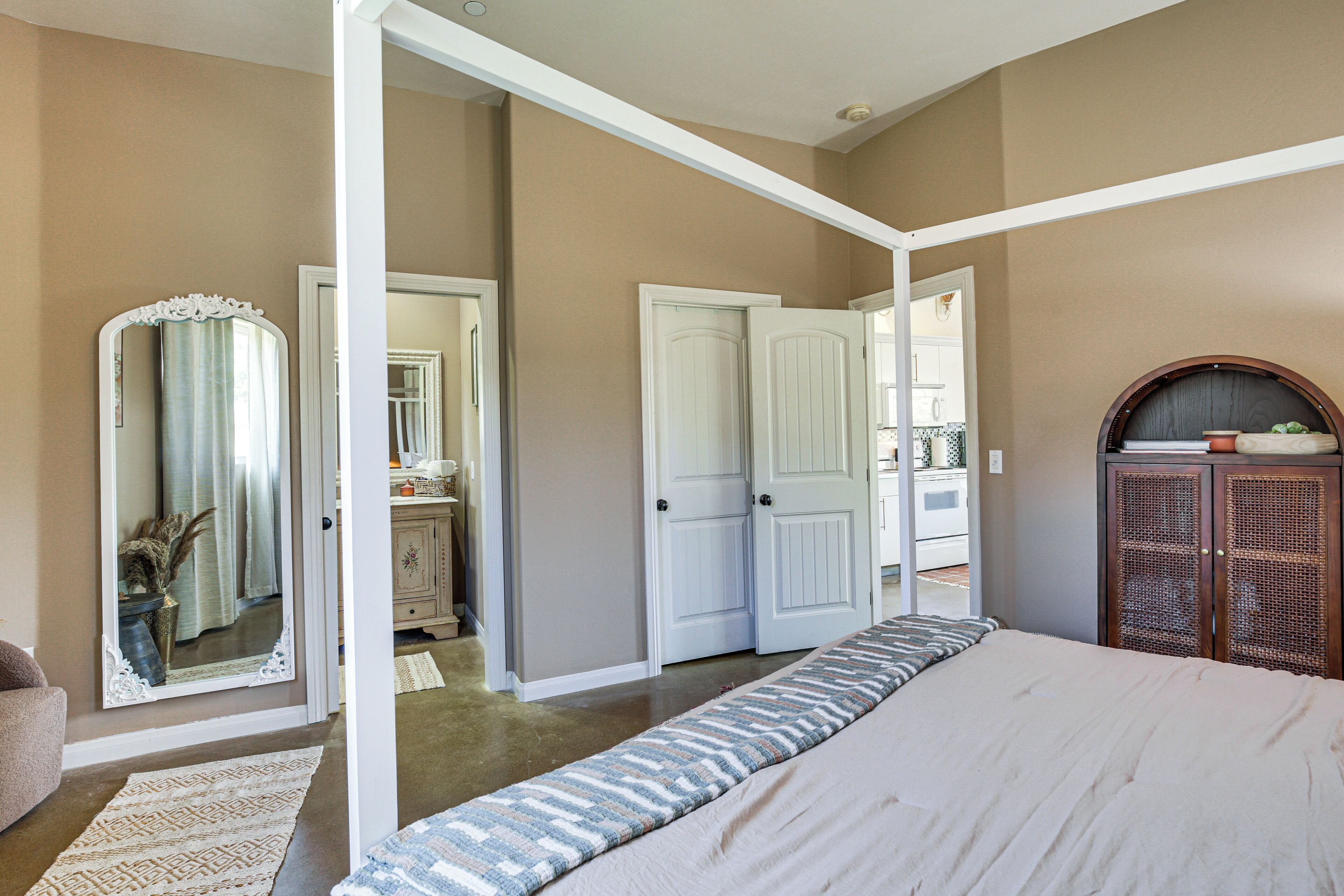Une chambre à coucher avec un grand lit, un dressing, un miroir et une armoire en bois.