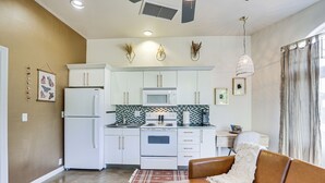 A modern kitchen with white cabinets, a microwave, and a refrigerator. There is a dining area with a brown leather couch and a table. - Cozy Alpine Cottage Near Casinos & Trails! (Alpine)