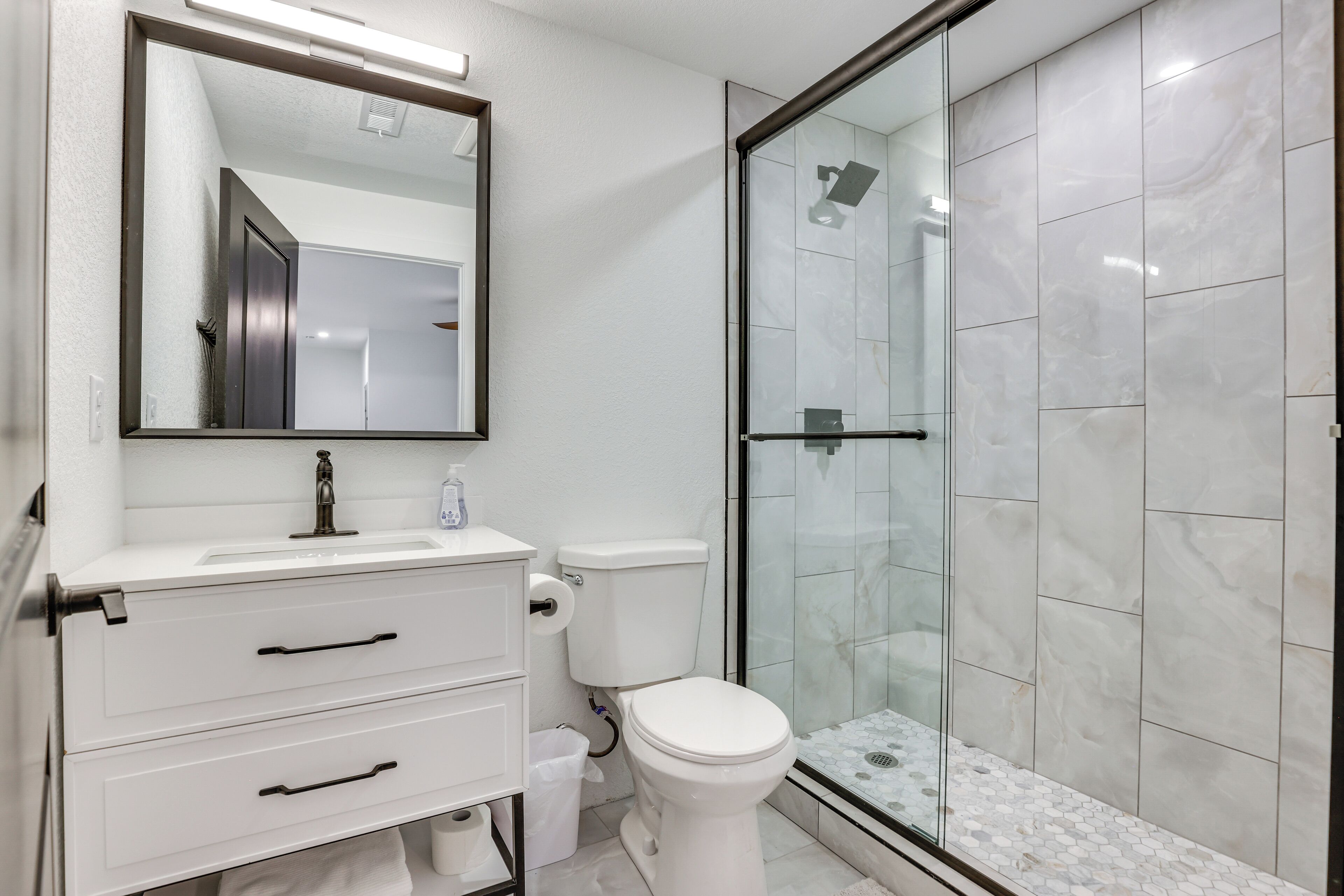 Un bagno moderno con un mobile lavabo bianco, un WC e una cabina doccia in vetro.