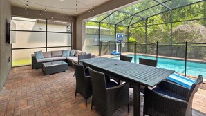An outdoor patio with a pool, a basketball hoop, and a seating area with a sofa and chairs. - PROMO Rebel Reef 8 BR Themed Villa, Pool, Arcade by Blue Sky Villas (Kissimmee)
