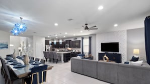 A modern living room with a dining area, kitchen, and a large TV. - PROMO Rebel Reef 8 BR Themed Villa, Pool, Arcade by Blue Sky Villas (Kissimmee)
