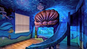 A room with a large seashell-shaped bed, a window with blinds, and a mural of underwater scenes. - PROMO Rebel Reef 8 BR Themed Villa, Pool, Arcade by Blue Sky Villas (Kissimmee)