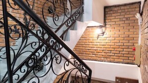 A staircase with ornate black metal railings and a brick wall. - Moc An by Bay Hotel (Hanoi)