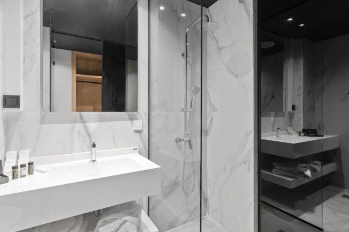 A modern bathroom with a glass-enclosed shower, a white sink, and a mirror.