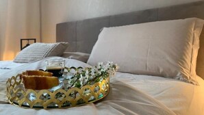 Ein ordentlich bezogenes Bett mit einem dekorativen Tablett, das ein Gebäck, ein Getränk und Blumen enthält.