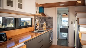 Een moderne keuken met houten aanrecht, een inbouwoven en een raam met uitzicht op een schilderachtig panorama.