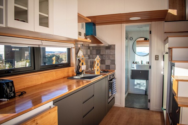 Une cuisine moderne avec des plans de travail en bois, un four encastré et une fenêtre donnant sur un paysage pittoresque.