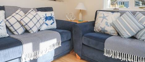 A cozy living room with two sofas, a lamp, and a painting on the wall.