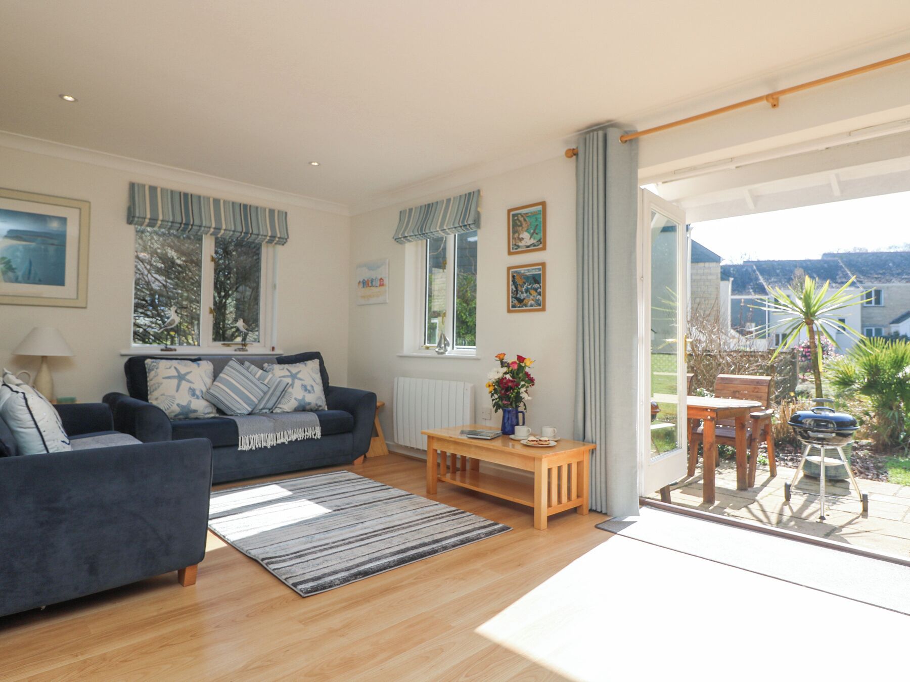 Un salon chaleureux avec un canapé, une table basse et une vue sur le jardin grâce à une grande fenêtre.