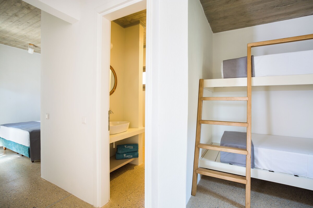 Quarto com beliche, banheiro pequeno com pia e armário com prateleiras.