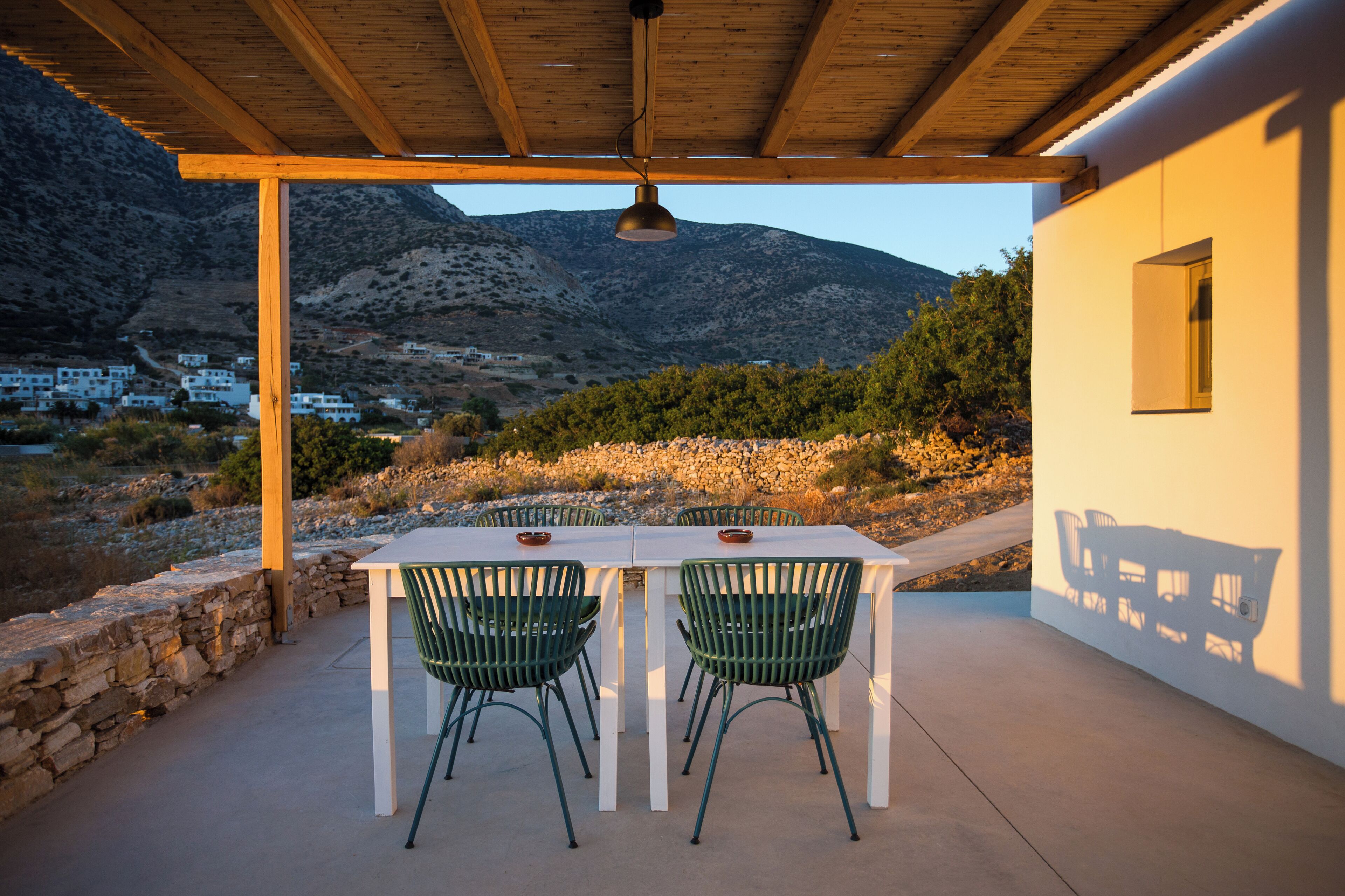 An outdoor patio with a table and chairs, overlooking a mountainous landscape.